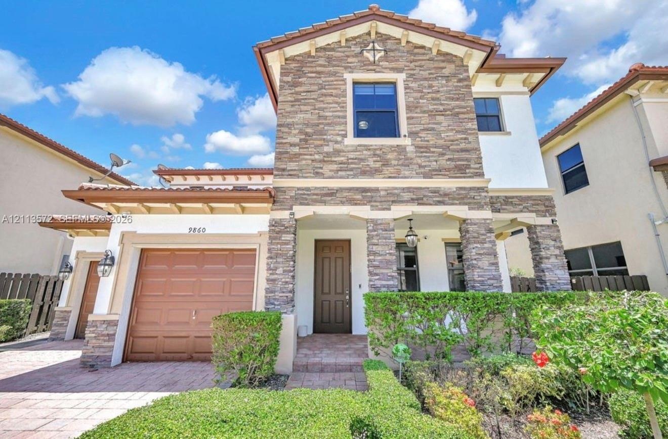 Two-story exterior featuring stone veneer accents, a tiled roof, a paved driveway, and an arched entry with recessed lighting
