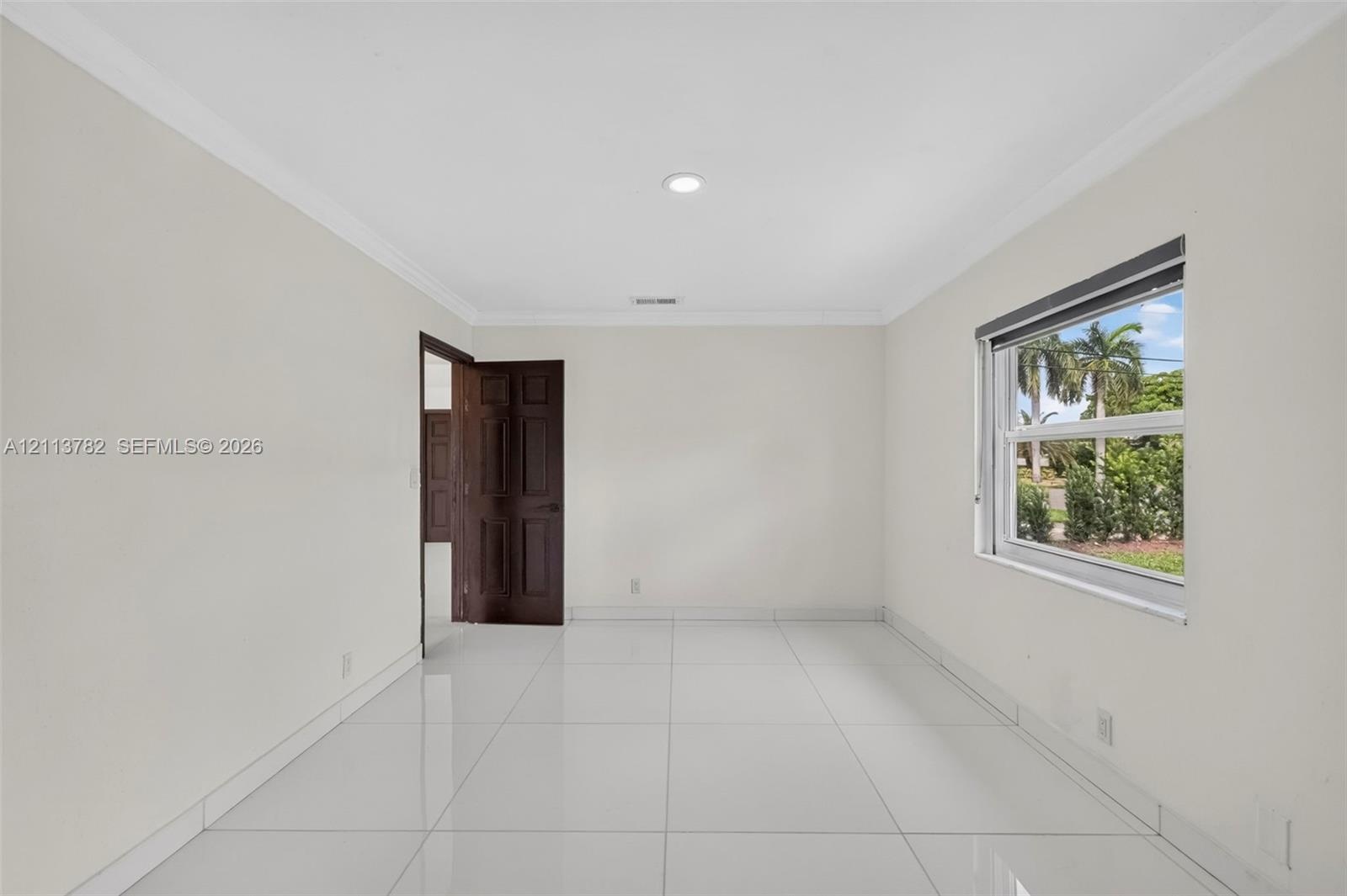 Interior space featuring large-format tile flooring, crown molding, recessed lighting, and a multi-panel wood door