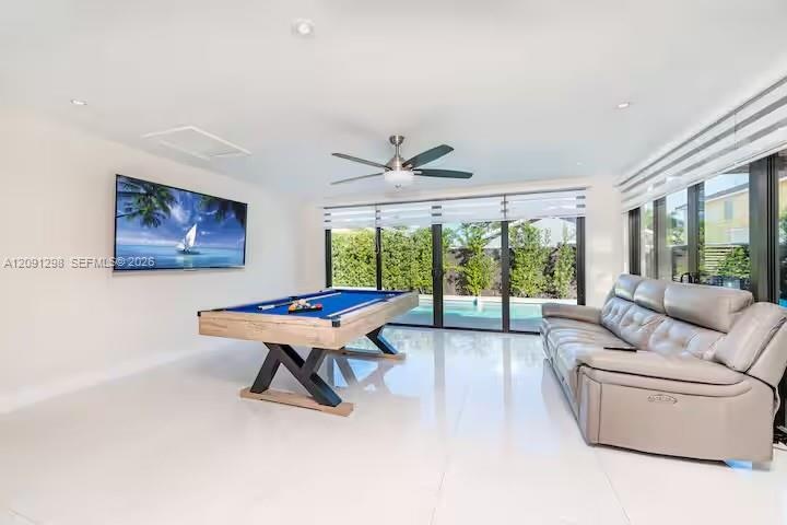 Spacious interior featuring high-gloss tile flooring, recessed ceiling lighting, a brushed-nickel ceiling fan, and extensive floor-to-ceiling glass sl
