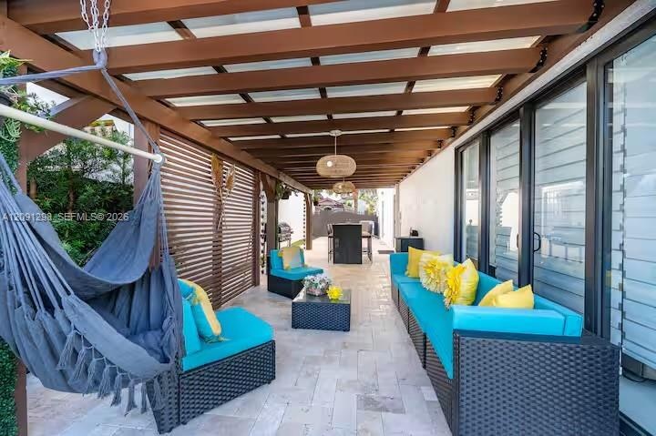 Covered patio featuring a timber-frame pergola, natural stone flooring, slatted wood privacy screen, and recessed pendant lighting