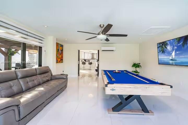 Polished tile flooring, wall-mounted ductless air conditioning unit, ceiling fan with integrated lighting, and floor-to-ceiling glass sliding doors