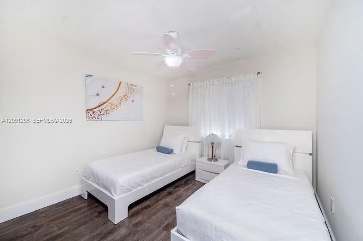 Room featuring dark-toned wood-finish flooring, a white ceiling fan with integrated lighting, and neutral wall paint