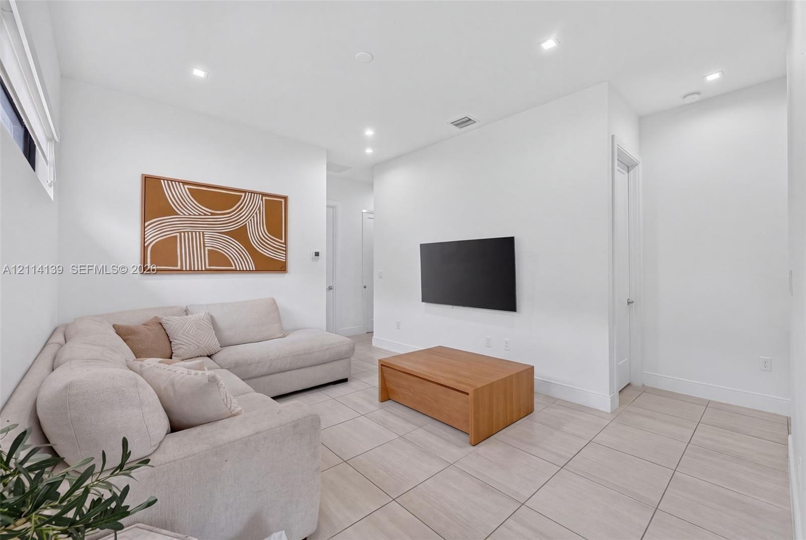 Neutral-toned large-format tile flooring, recessed ceiling lighting, and smooth-finish walls