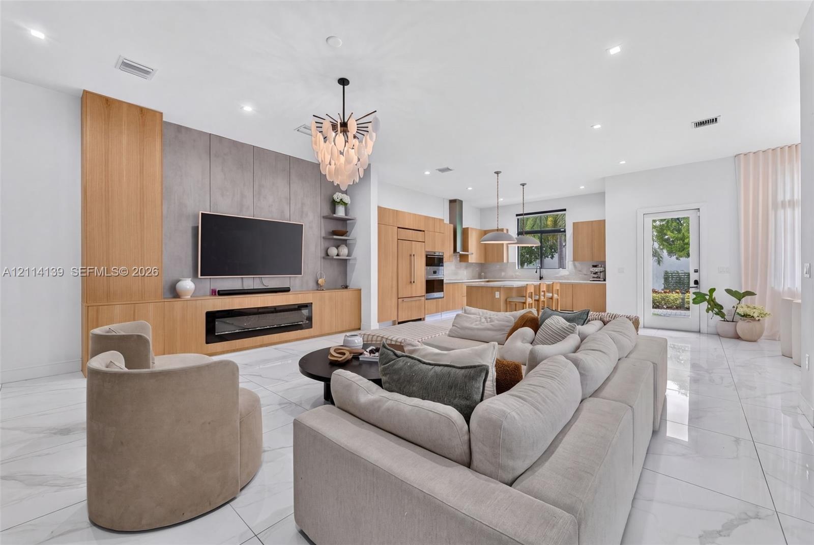 Large-format tile flooring, custom light-toned cabinetry, integrated fireplace, expansive stone-finish feature wall, and recessed ceiling lighting