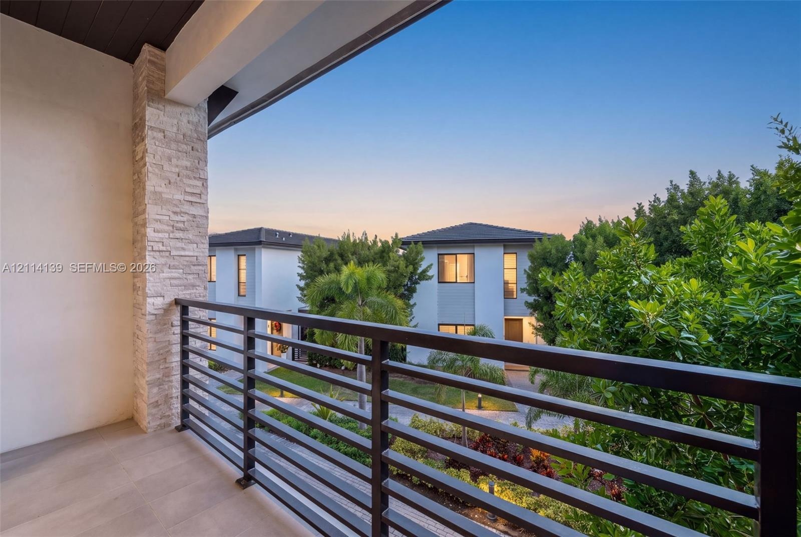 Covered balcony featuring stone-clad pillar, metal railing, and tile flooring