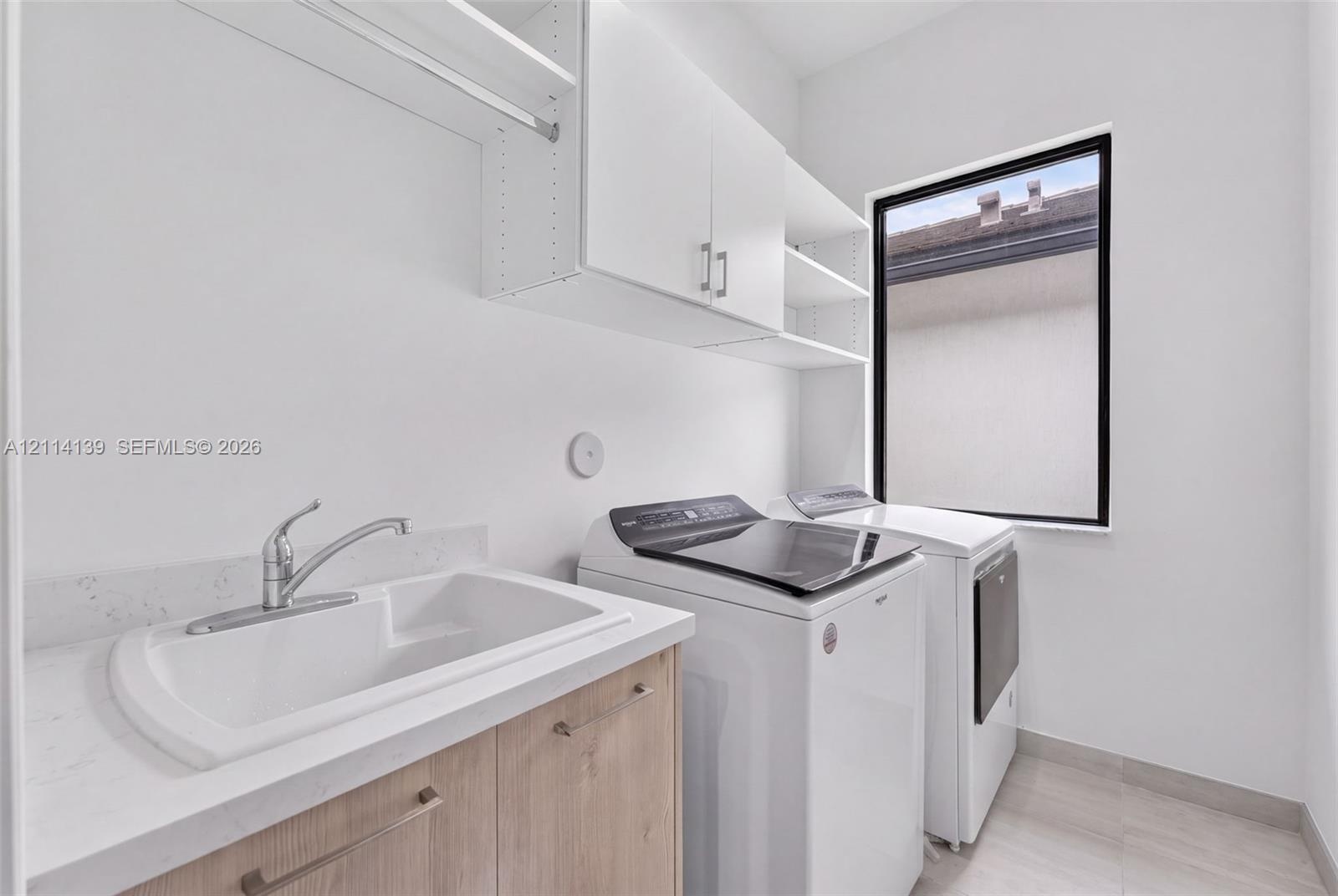 Utility space featuring a drop-in sink, stone-composite countertop, light-finish cabinetry, white upper storage cabinets, and tile flooring