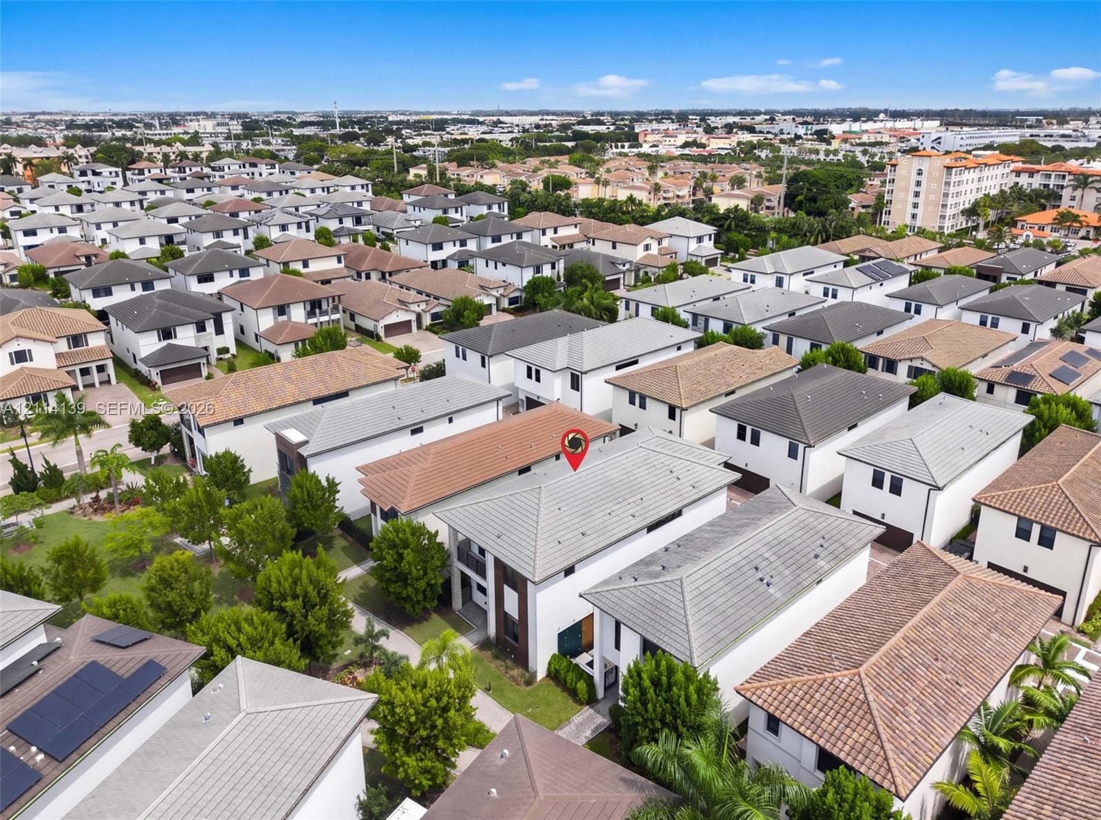Aerial perspective featuring a multi-story residence with a concrete tile roof, light-toned exterior facade, and mature landscaping