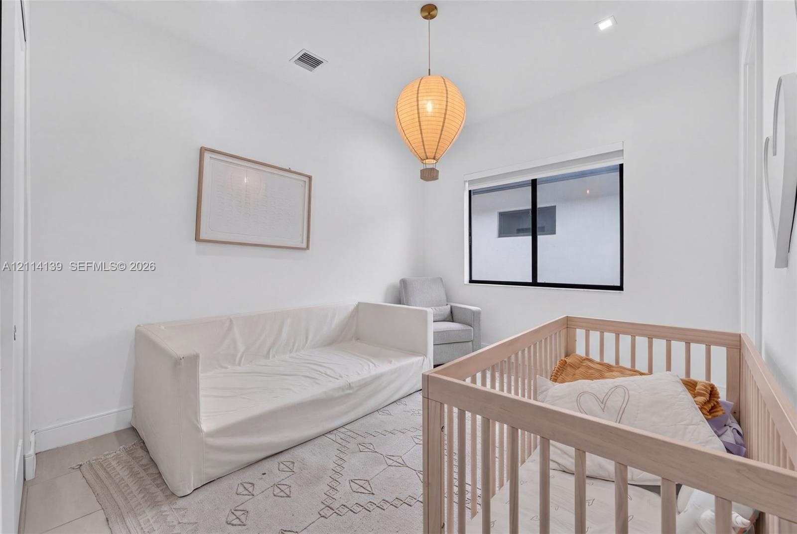 Neutral interior featuring a large window with black framing, recessed ceiling lighting, and a spherical pendant fixture