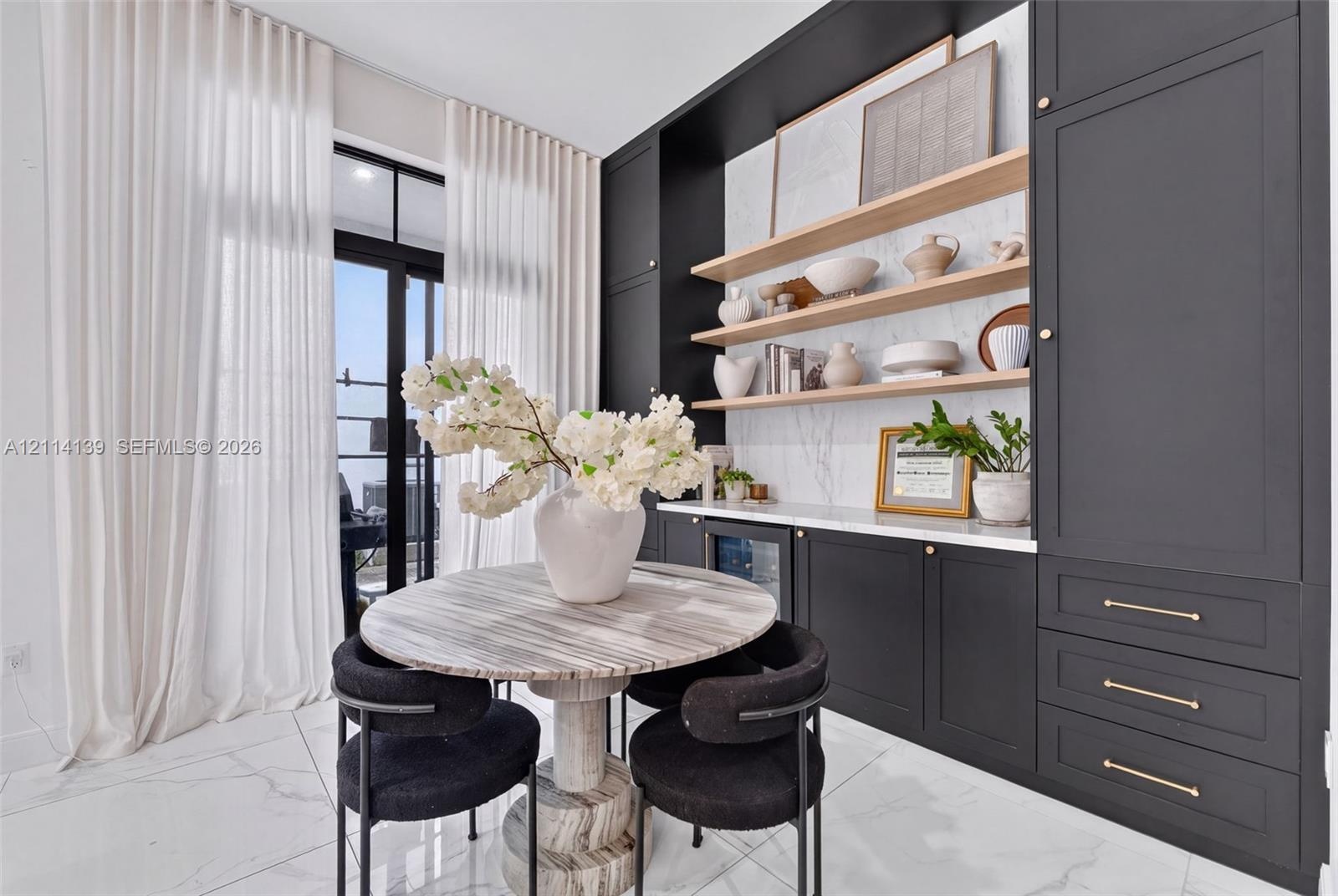 Built-in cabinetry with matte finish, stone-surface countertop, integrated beverage refrigerator, light wood floating shelving, and large-format tile 