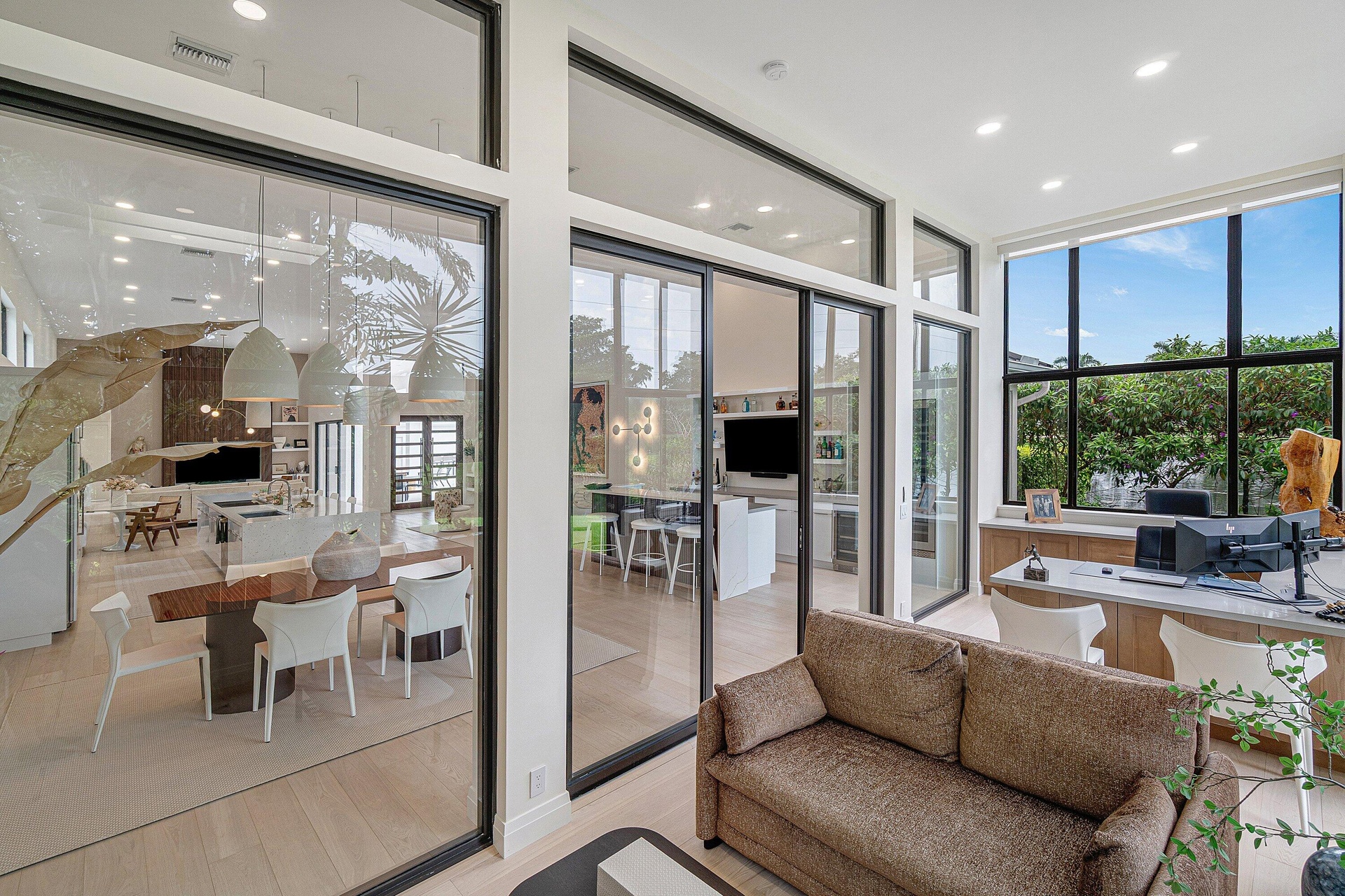 Distinctive glass-enclosed office with a built-in desk, and an inviting media lounge with a TV and a convertible sofa.