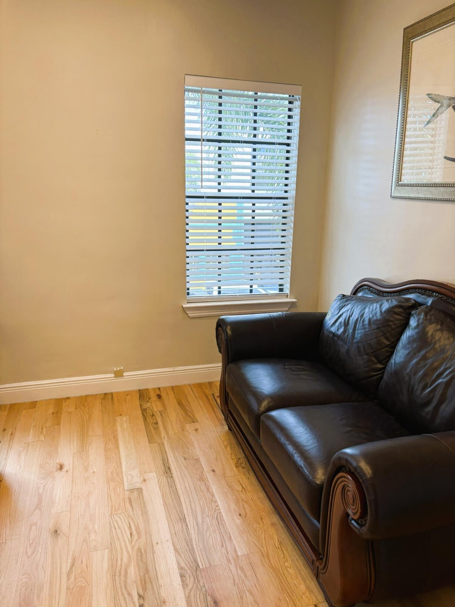 Wood-finish flooring paired with a single-pane window featuring horizontal blinds