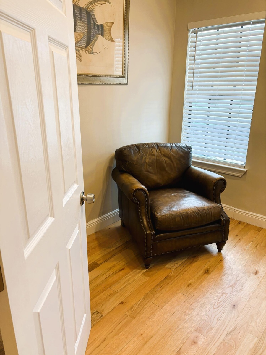 Wood-finish flooring, multi-pane window with adjustable slat blinds, and classic paneled interior door