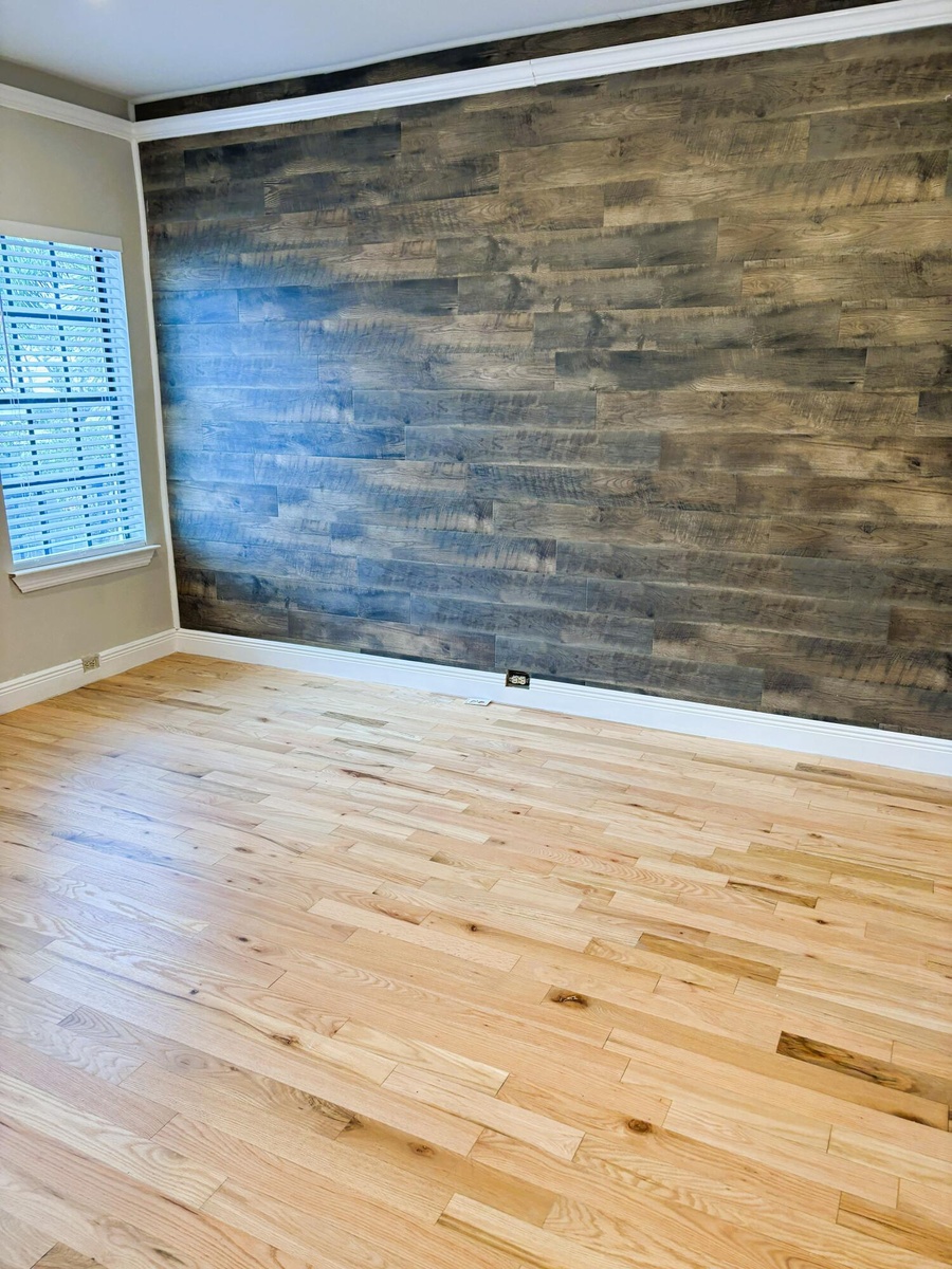 Wood-plank accent wall featuring a rustic finish, light-toned wood-finish flooring, and multi-pane window with interior shutters