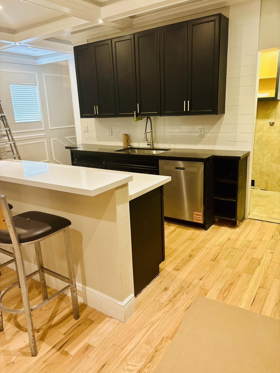 Kitchen featuring custom dark-toned cabinetry, quartz countertops, stainless steel undermount sink with goose-neck faucet, integrated dishwasher, and 