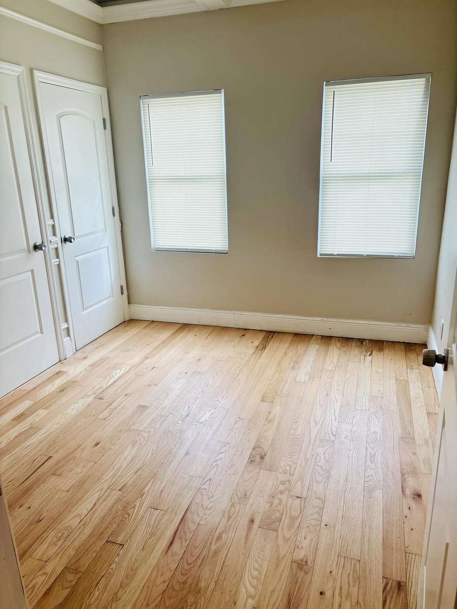 Interior space featuring wood-finish flooring, two dual-pane windows with fitted blinds, and two solid-core paneled doors