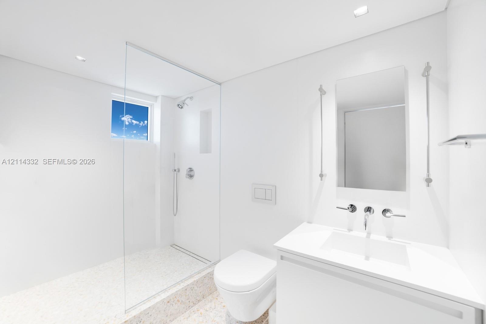 Minimalist bathroom featuring a glass-enclosed shower with a built-in recessed shelf, wall-mounted dual-flush toilet, integrated vanity with a rectang