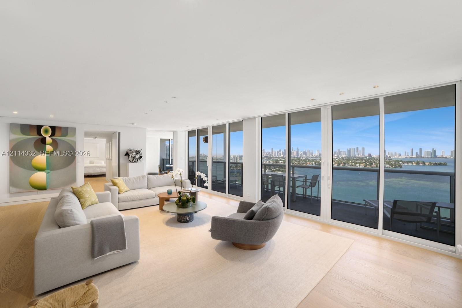 Open-concept living area featuring floor-to-ceiling glass sliding doors, recessed lighting, wood-finish flooring, and a private balcony