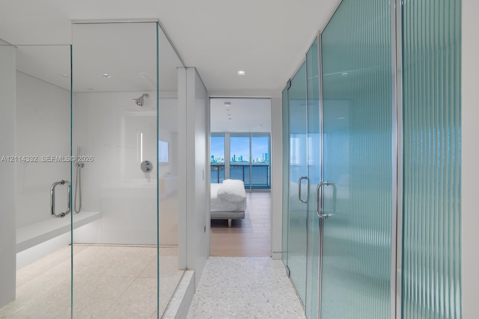 Enclosed shower with built-in bench, frameless glass door, ribbed glass privacy panel, and recessed lighting