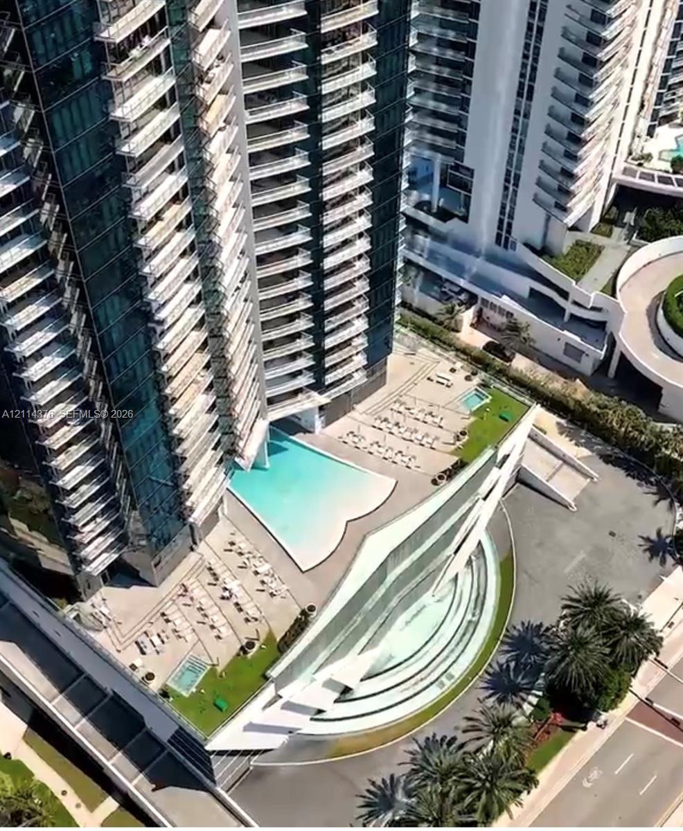 High-rise architectural exterior featuring tiered glass balconies, an expansive multilevel swimming pool area, multi-level terrace decks, and landscap