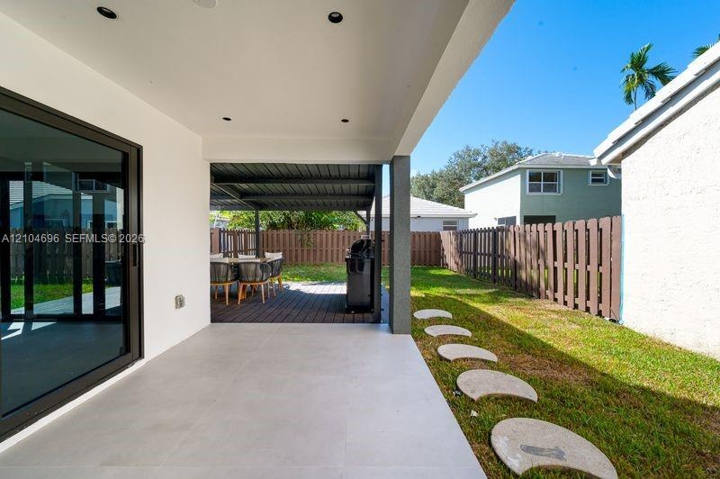 Covered patio featuring large-format porcelain tile flooring and recessed lighting, expanded by a secondary metal-framed outdoor structure with wood-f
