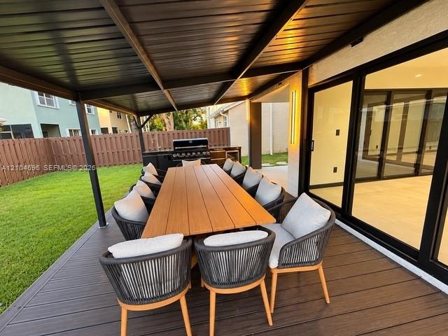 Covered patio featuring composite decking, built-in outdoor kitchen with grill, and large-format sliding glass doors