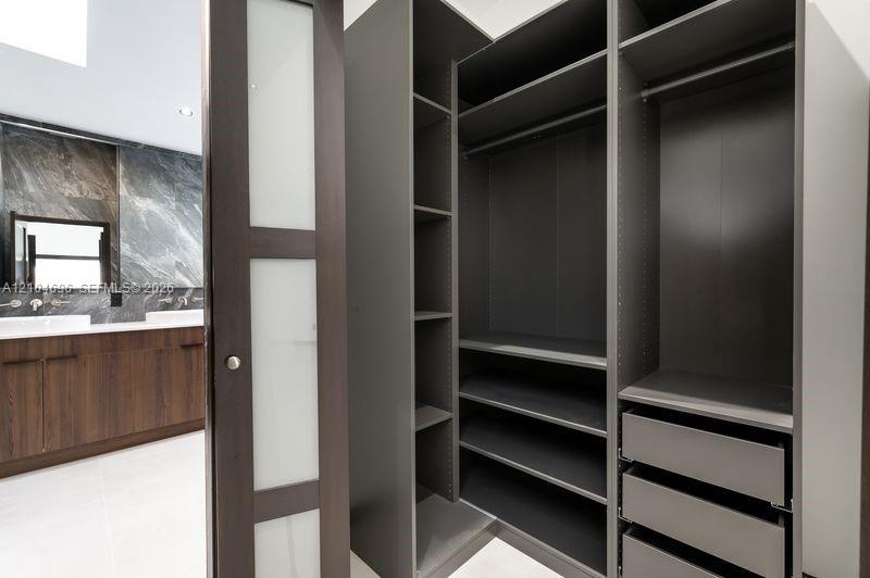 Custom built-in dark finish closet shelving with integrated drawers and hanging rods, featuring a sliding door with frosted glass panels, wood-finish 