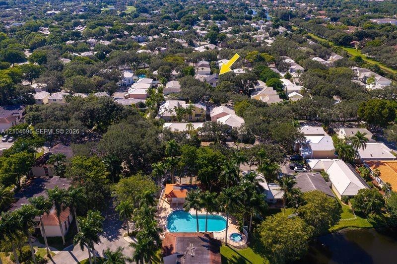 Aerial perspective highlighting a mature residential neighborhood featuring abundant tree canopy and a community recreation area with a swimming pool 