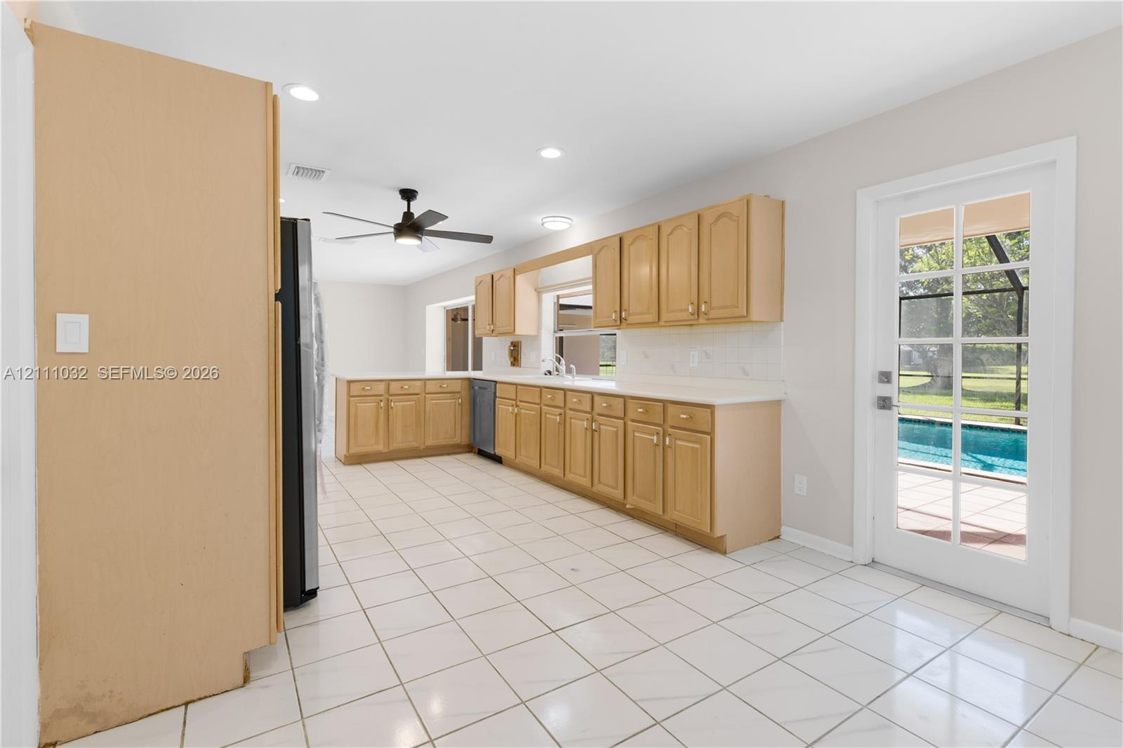 Kitchen featuring natural wood cabinetry, white countertops, ceramic tile flooring, recessed lighting, and a multi-lite door providing exterior access