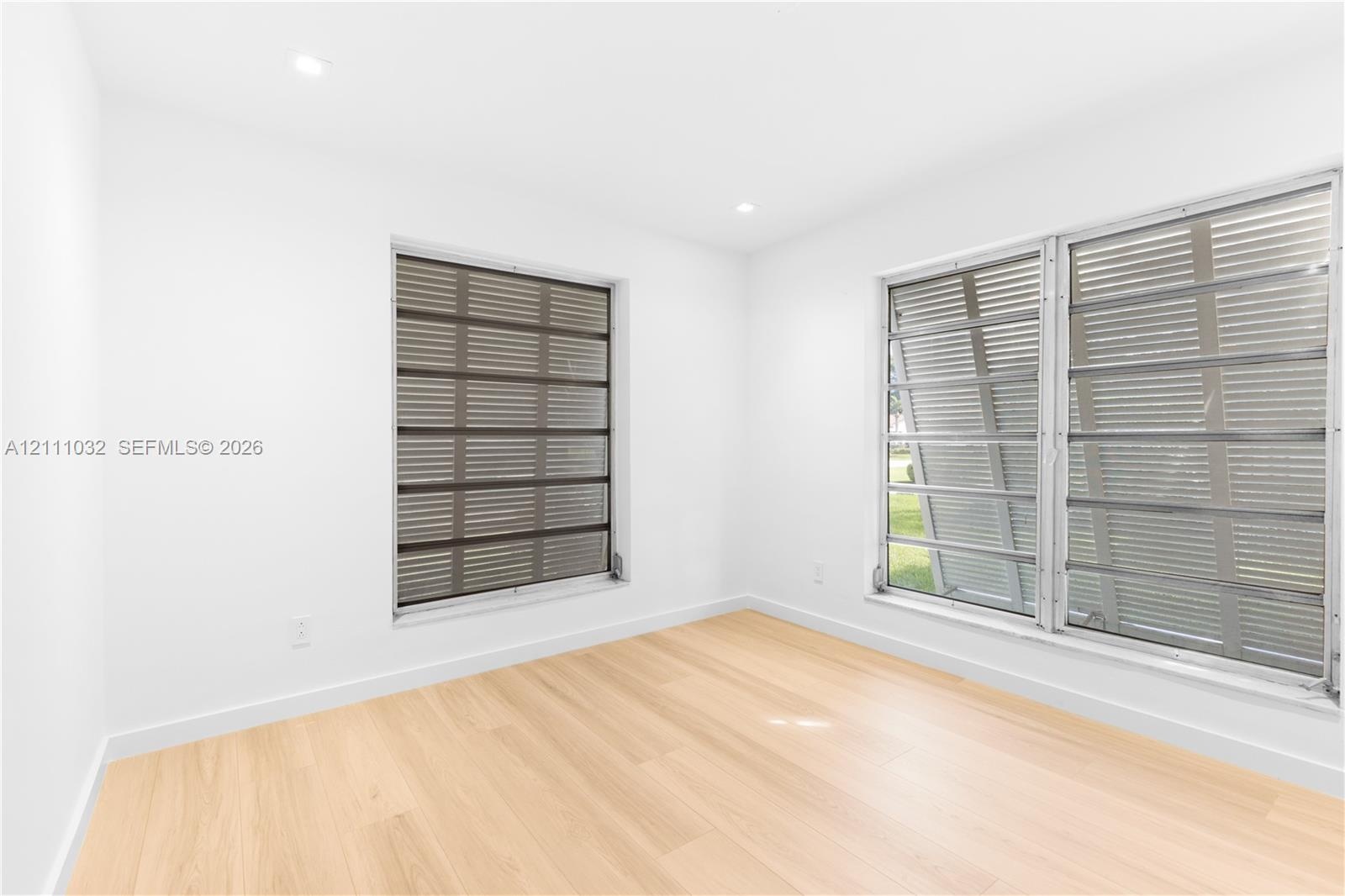 Wood-finish flooring, recessed lighting, and multiple jalousie windows
