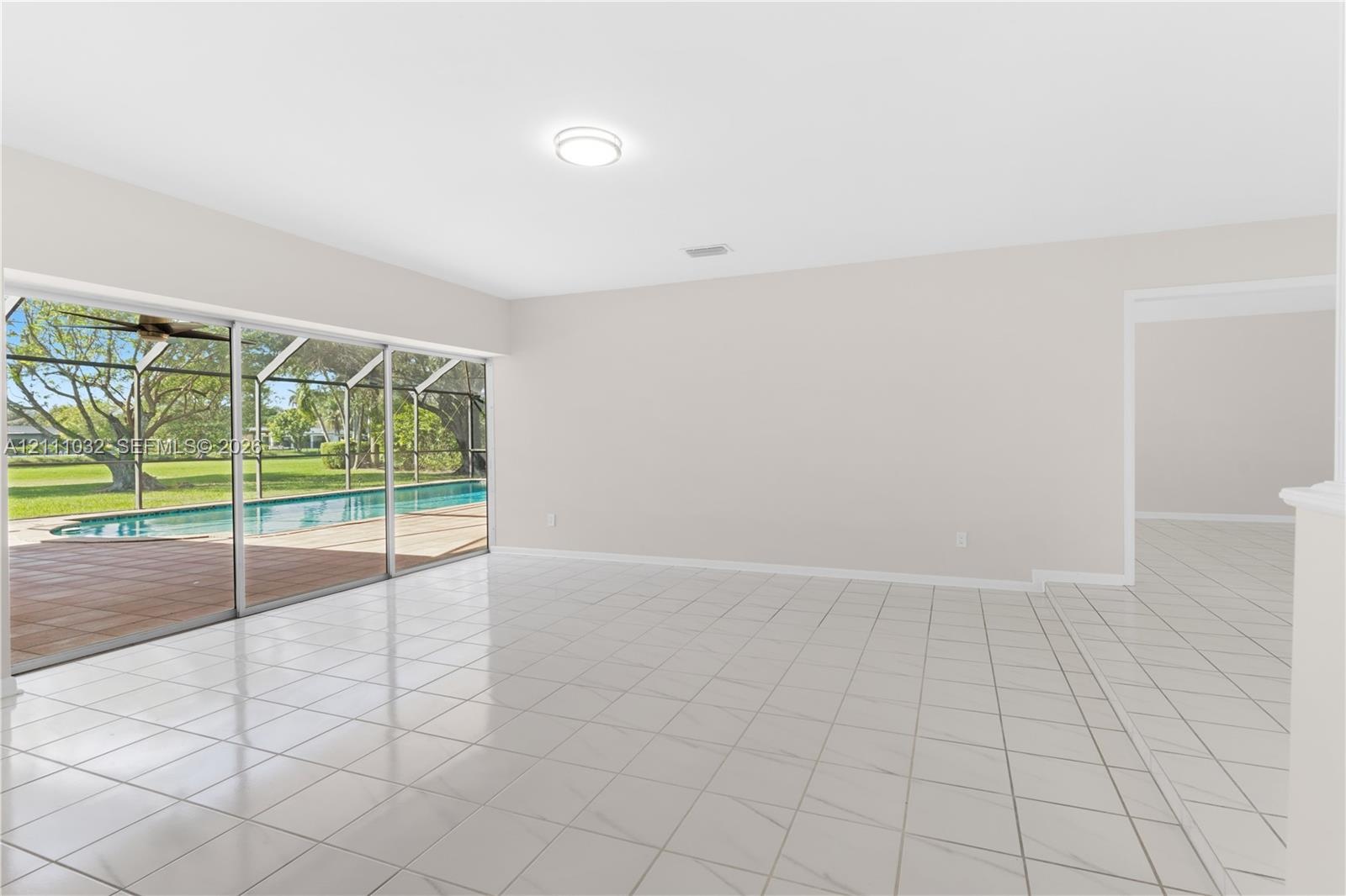 Open-concept interior featuring oversized tile flooring, recessed ceiling lighting, and expansive floor-to-ceiling sliding glass doors leading to a sc