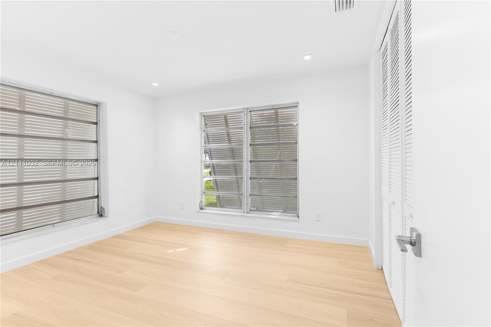 Bright interior featuring wood-finish flooring, recessed lighting, and louvered windows with horizontal blinds