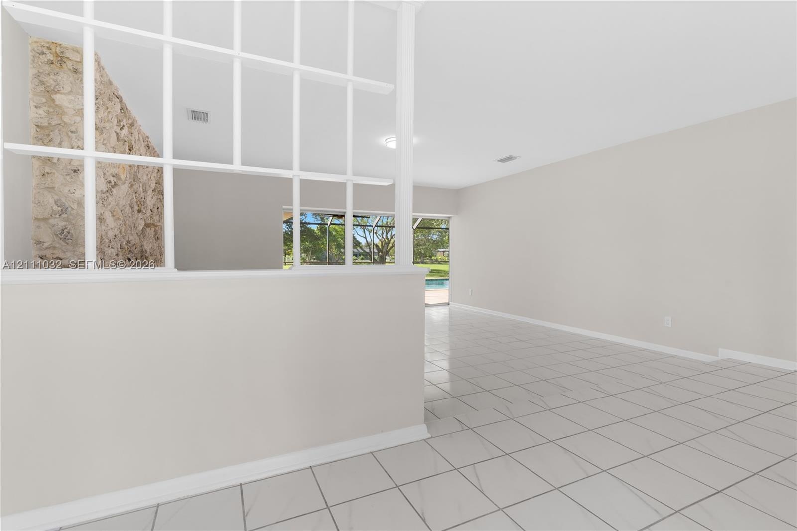 Living area featuring light-colored tile flooring, a white decorative lattice partition, and an interior stone accent wall