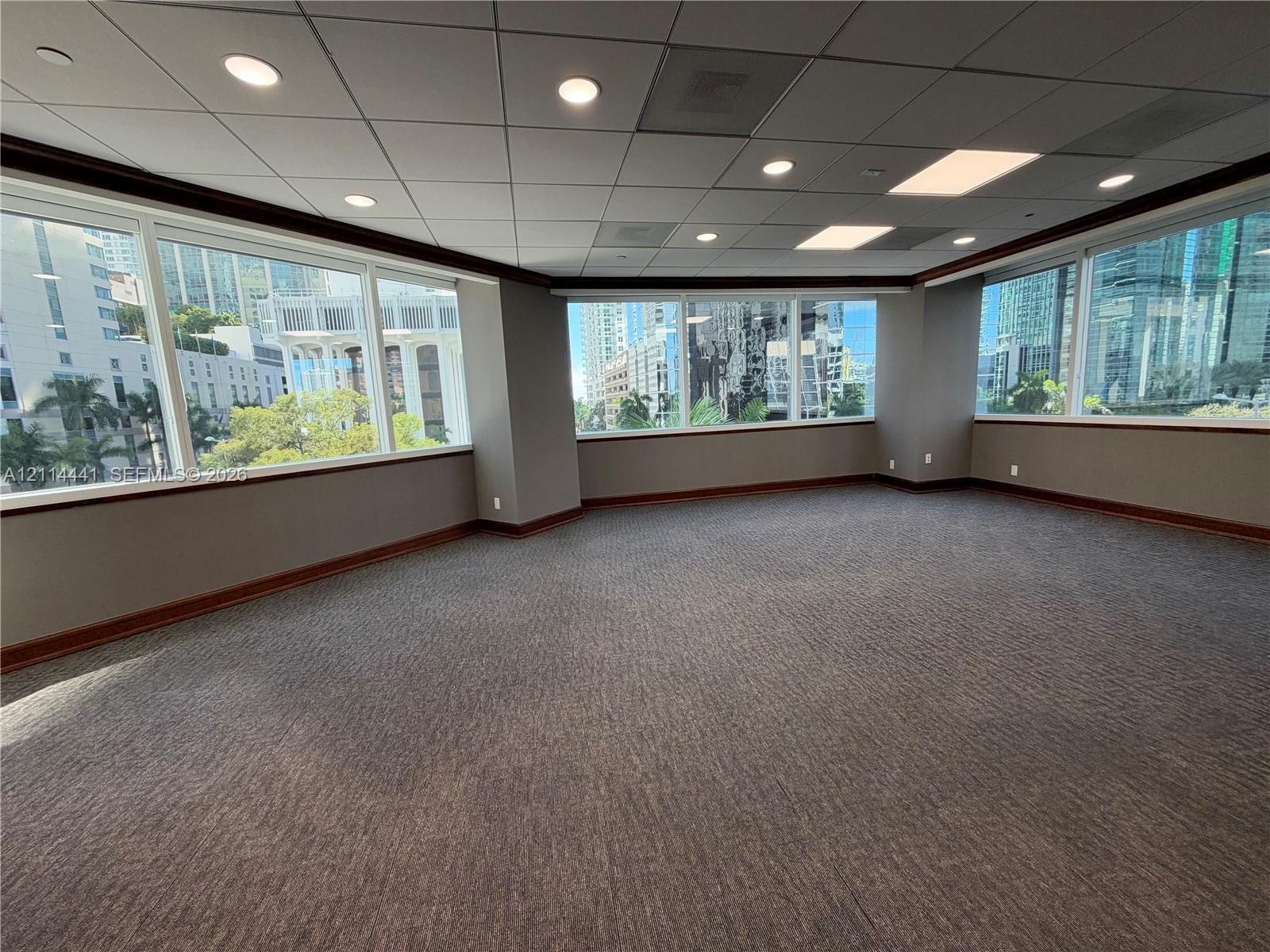 Expansive open-concept space featuring panoramic floor-to-ceiling windows, high-contrast dark wood-finish trim, recessed ceiling lighting, and wall-to