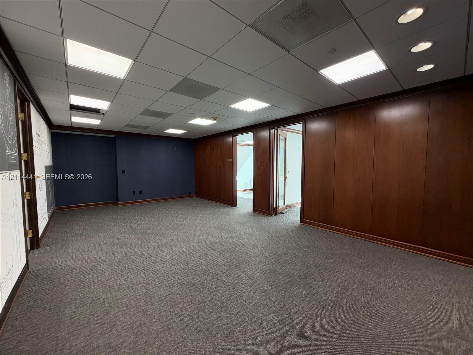 Wood-paneled walls, recessed ceiling lighting, drop ceiling, and carpeted flooring