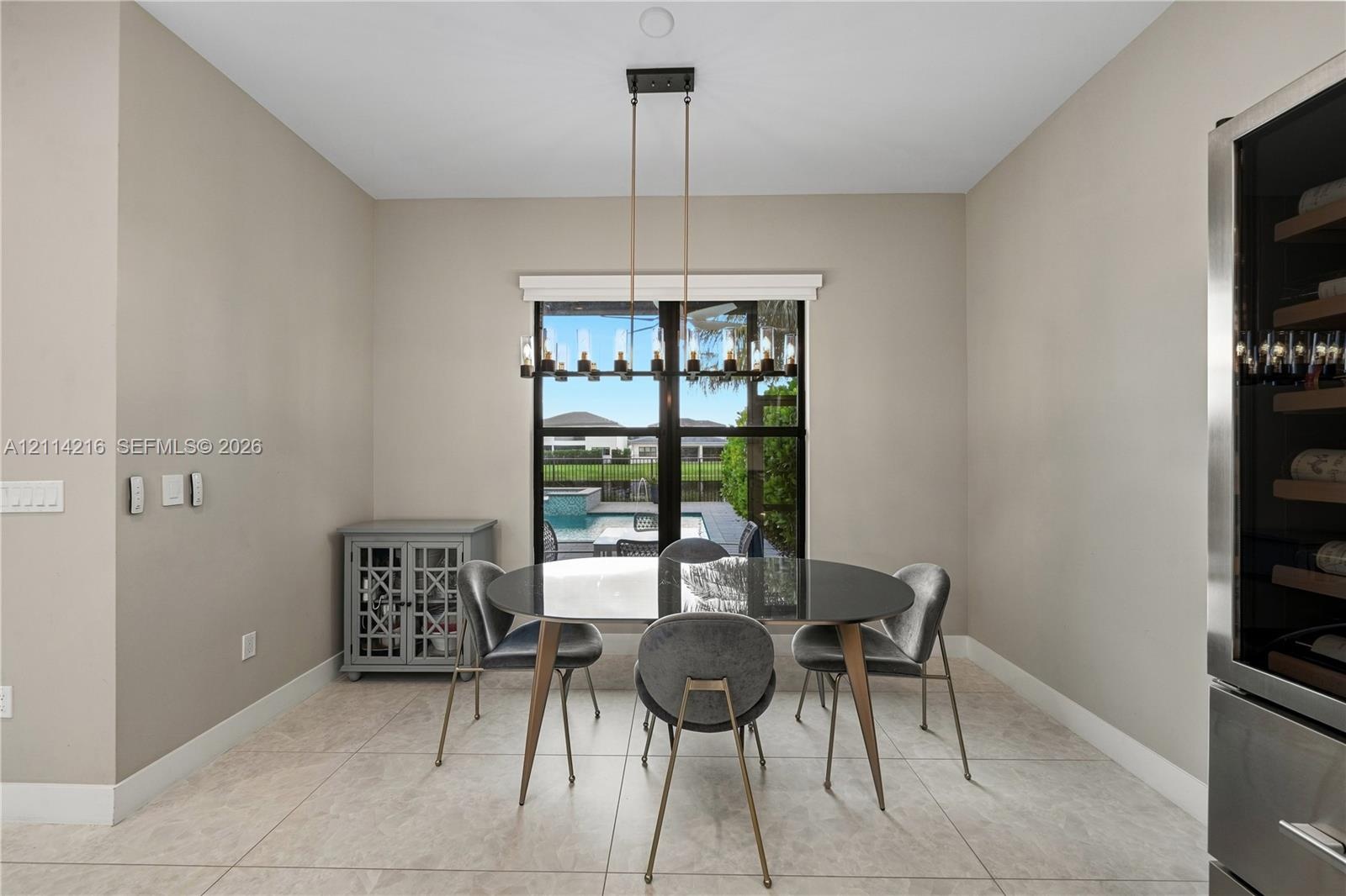 Dining area featuring large-format tile flooring, a linear multi-light pendant fixture, and a built-in stainless steel wine refrigerator