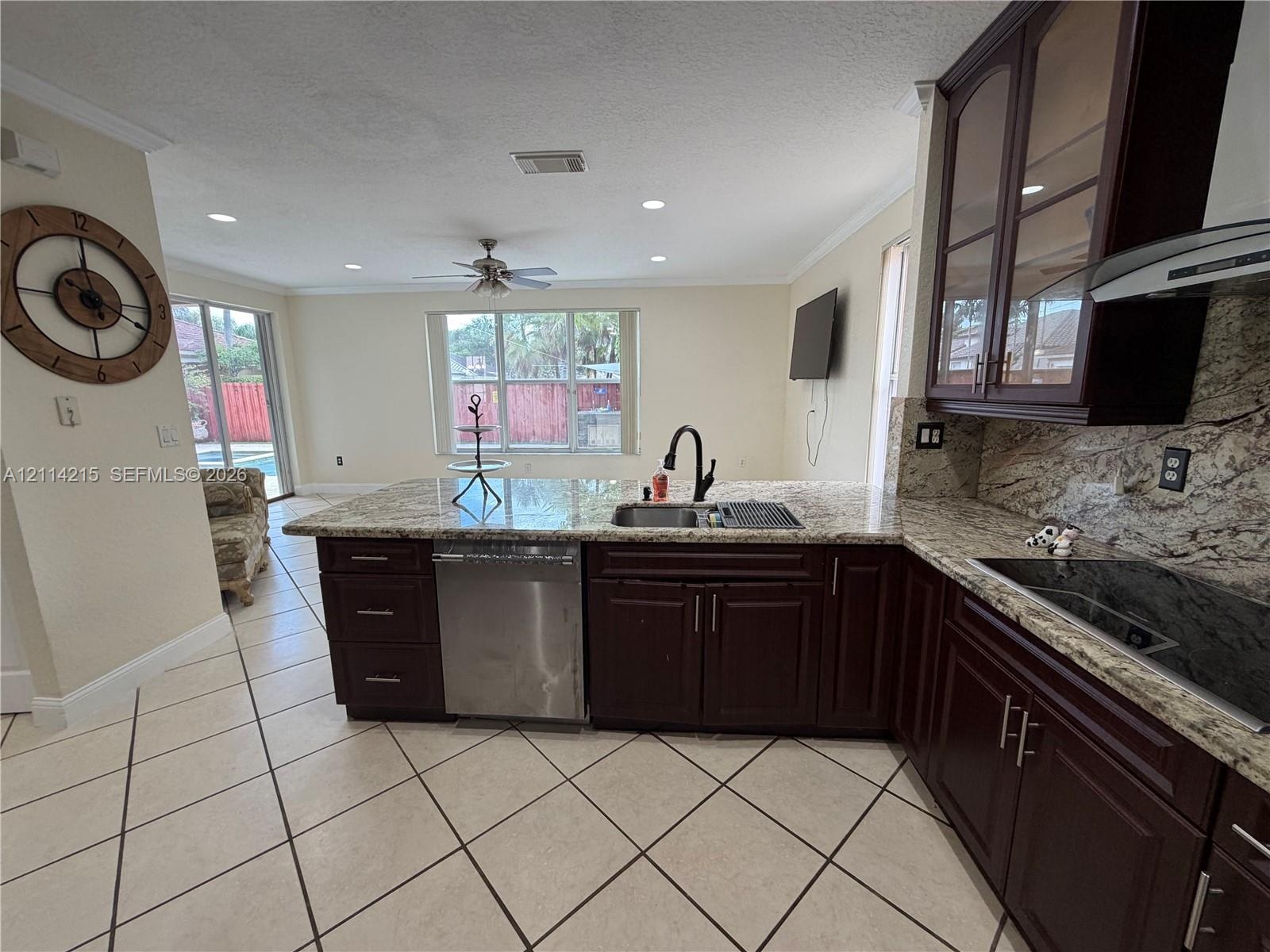 Kitchen featuring dark wood cabinetry, stone-surface countertops, stainless steel appliances, recessed ceiling lighting, and tile flooring