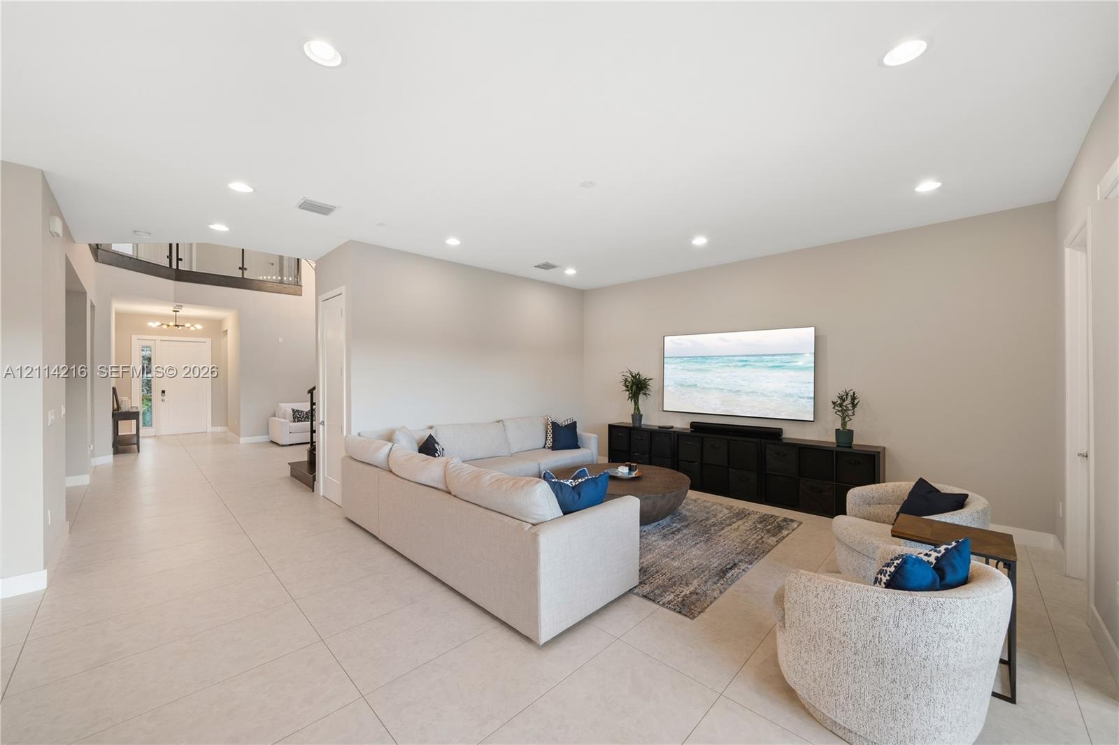 Open-concept living space featuring large-format tile flooring, recessed lighting, and a neutral color palette