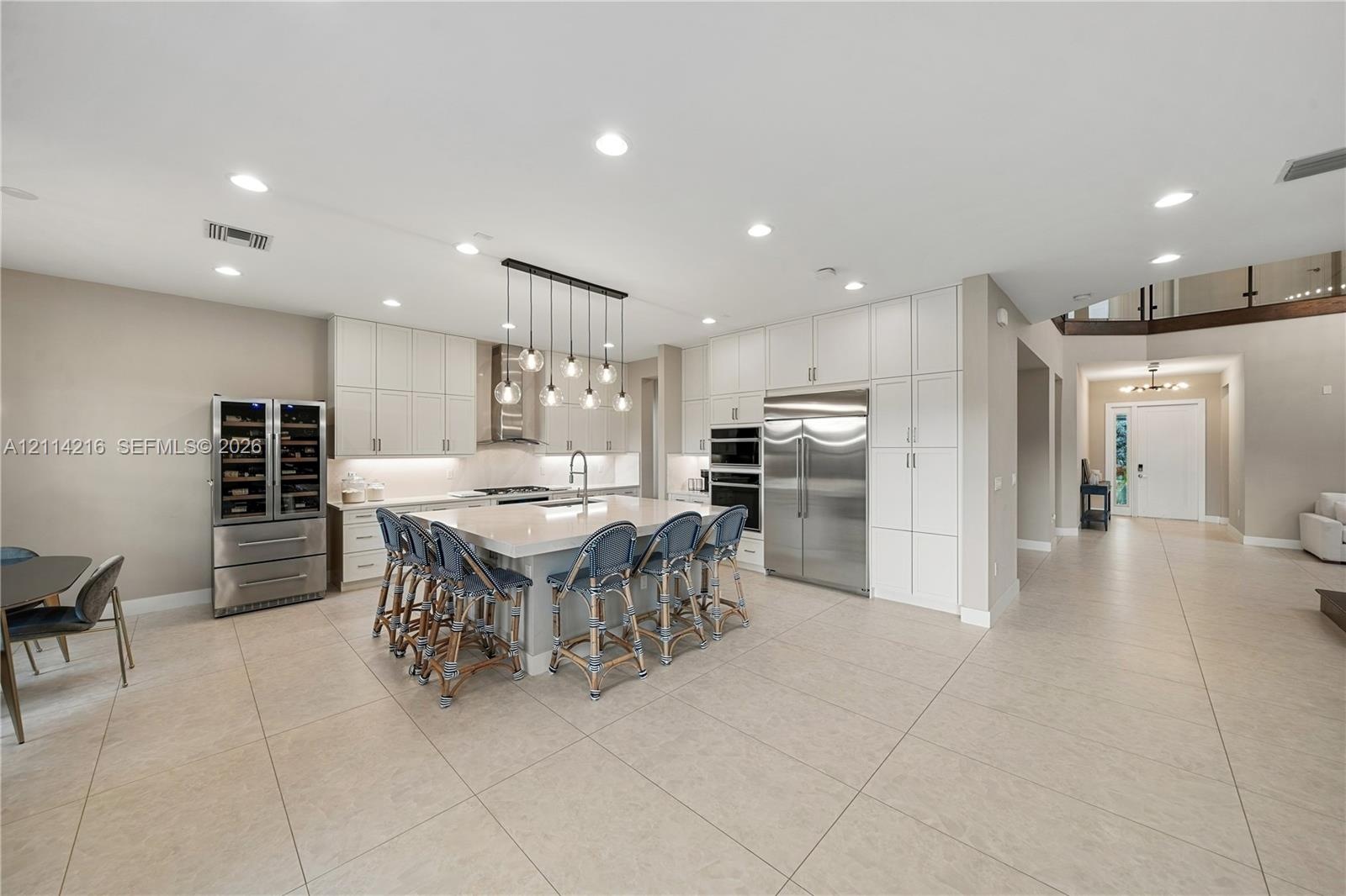 Kitchen featuring floor-to-ceiling white cabinetry, a large central island with quartz countertops, integrated stainless steel appliances, built-in wi