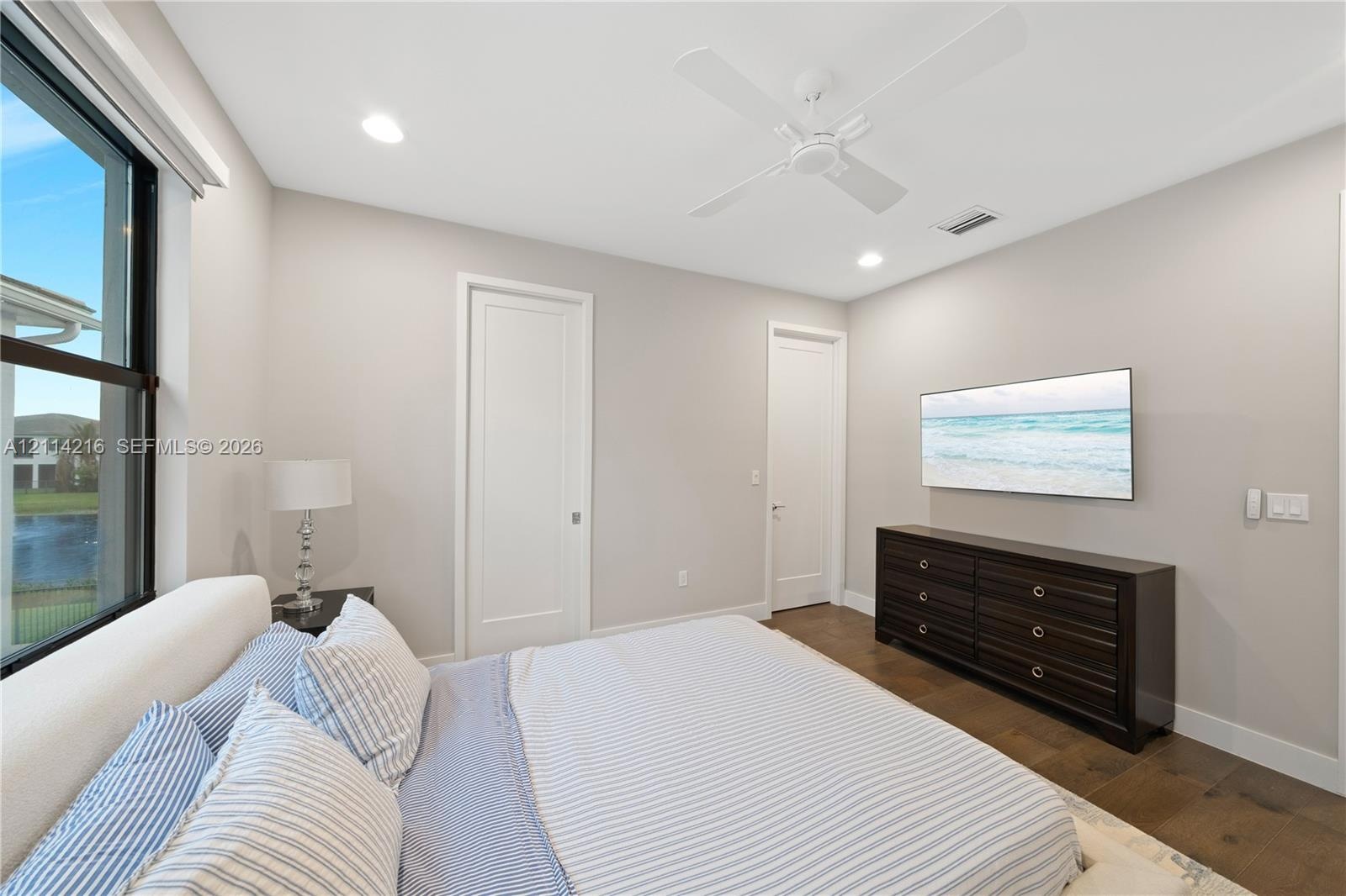 Neutral-toned interior featuring floor-to-ceiling windows, wood-finish flooring, a ceiling fan with integrated lighting, and solid-core doors