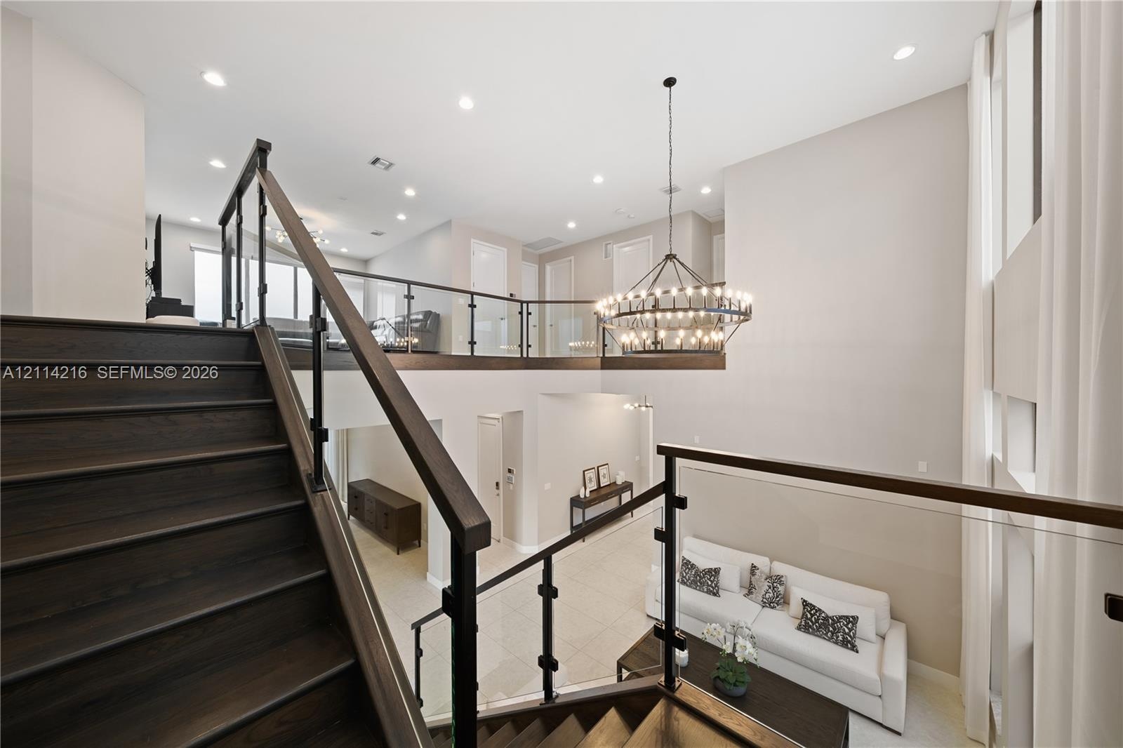 Staircase with wood-finish treads, dark railings, and glass panels