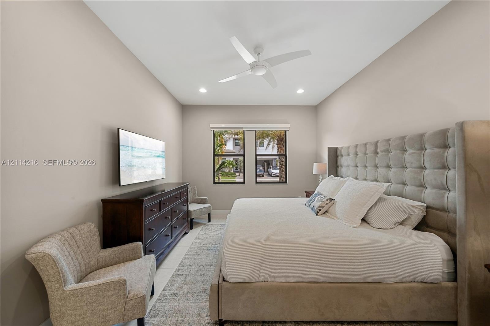 Neutral wall tones featuring a high ceiling with recessed lighting and a ceiling fan, complemented by windows with dark framing