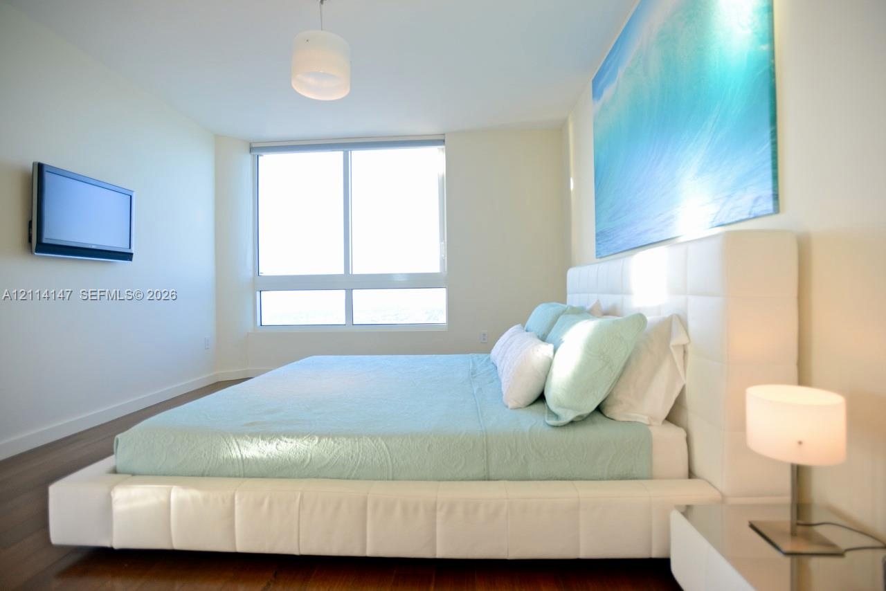 Wood-finish flooring, floor-to-ceiling windows, and wall-mounted television