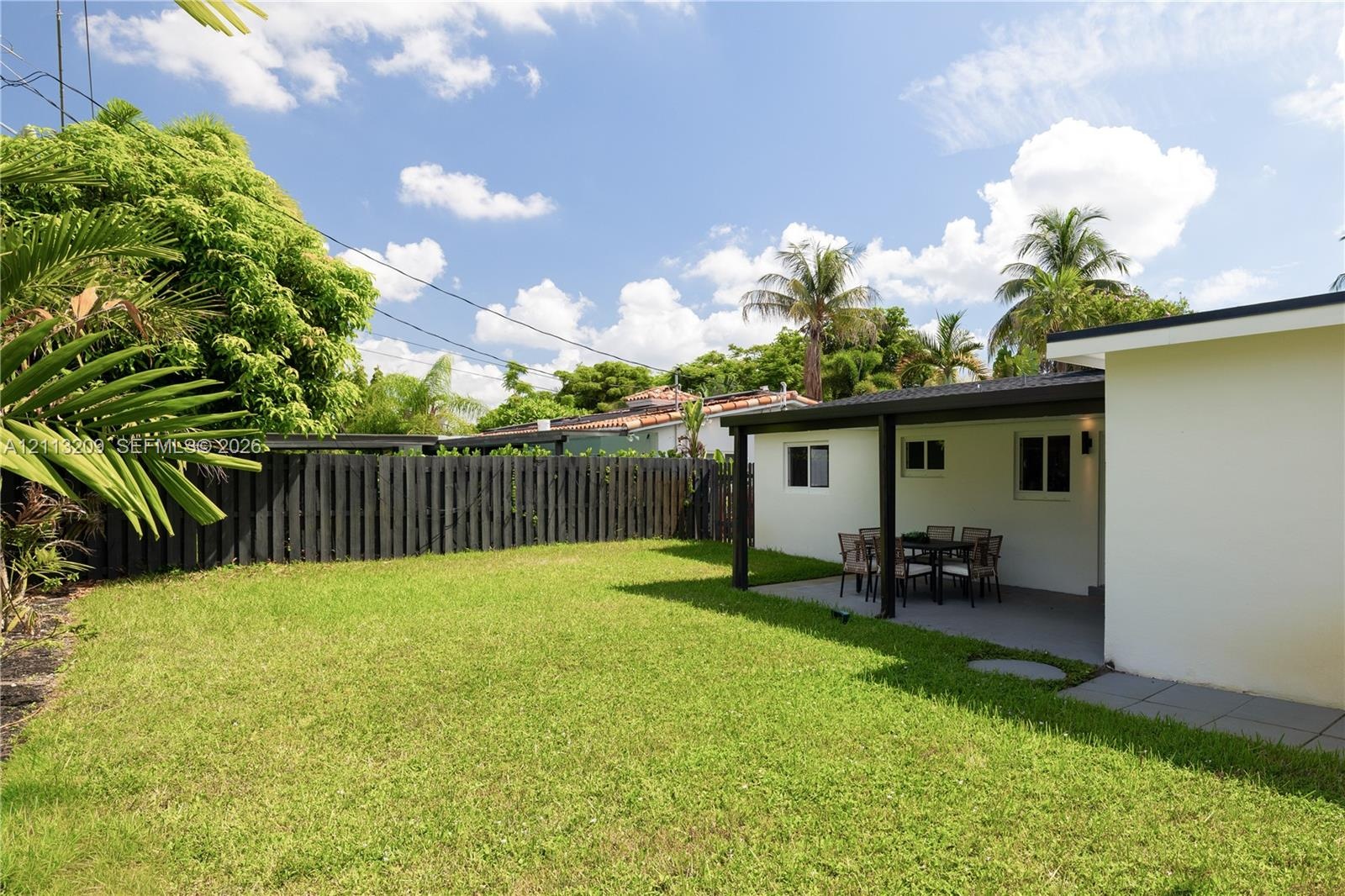 Backyard space featuring a covered patio, manicured lawn, and privacy fencing