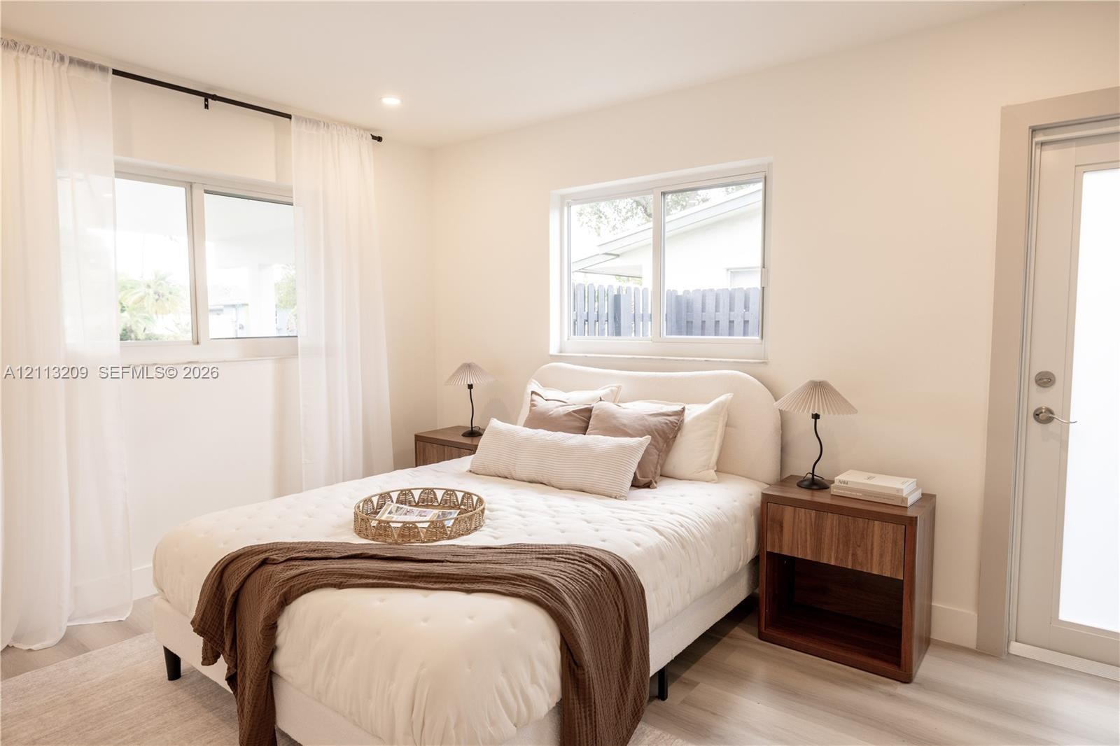 Neutral-toned interior featuring wood-finish flooring, dual sliding windows, and a glass-paneled exterior door
