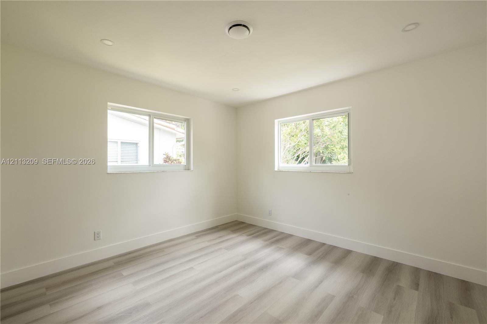 Neutral interior room featuring wood-finish flooring, recessed lighting, and dual sliding windows
