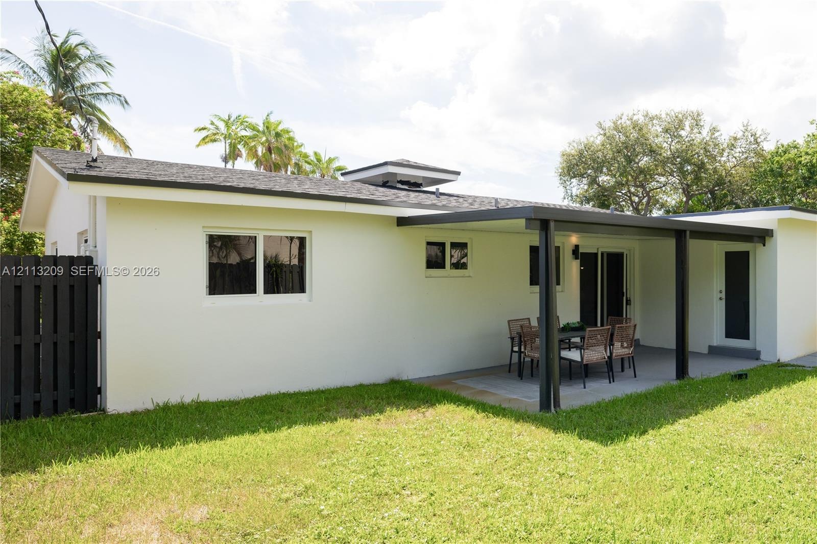 Exterior features include a covered patio, paved hardscaping, a fenced yard, and a shingled roof