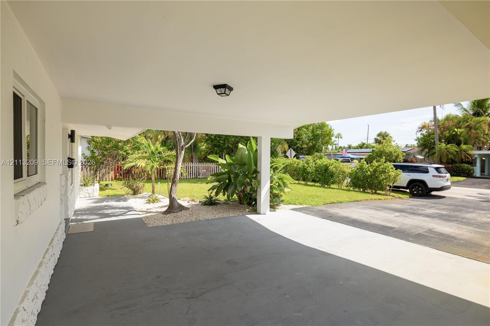 Covered carport with a concrete floor, integrated ceiling lighting, and exposed support pillar