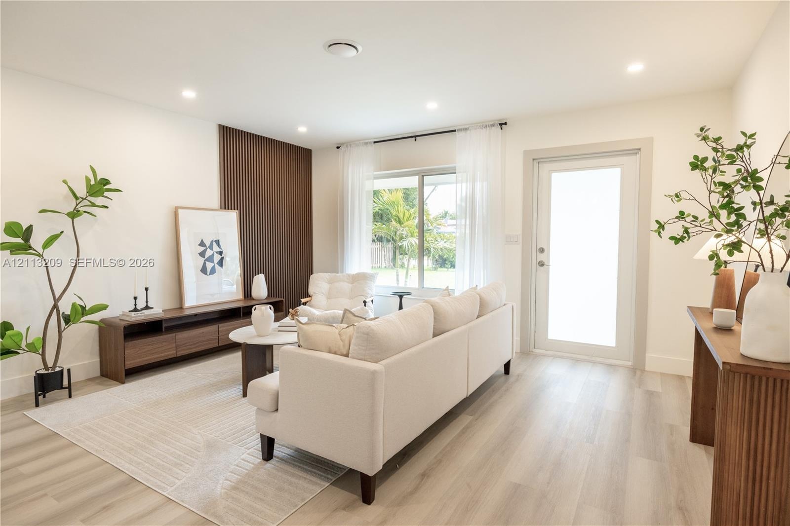 Living space featuring wood-finish flooring, vertical slat accent wall, recessed lighting, and a frosted glass-panel exterior door