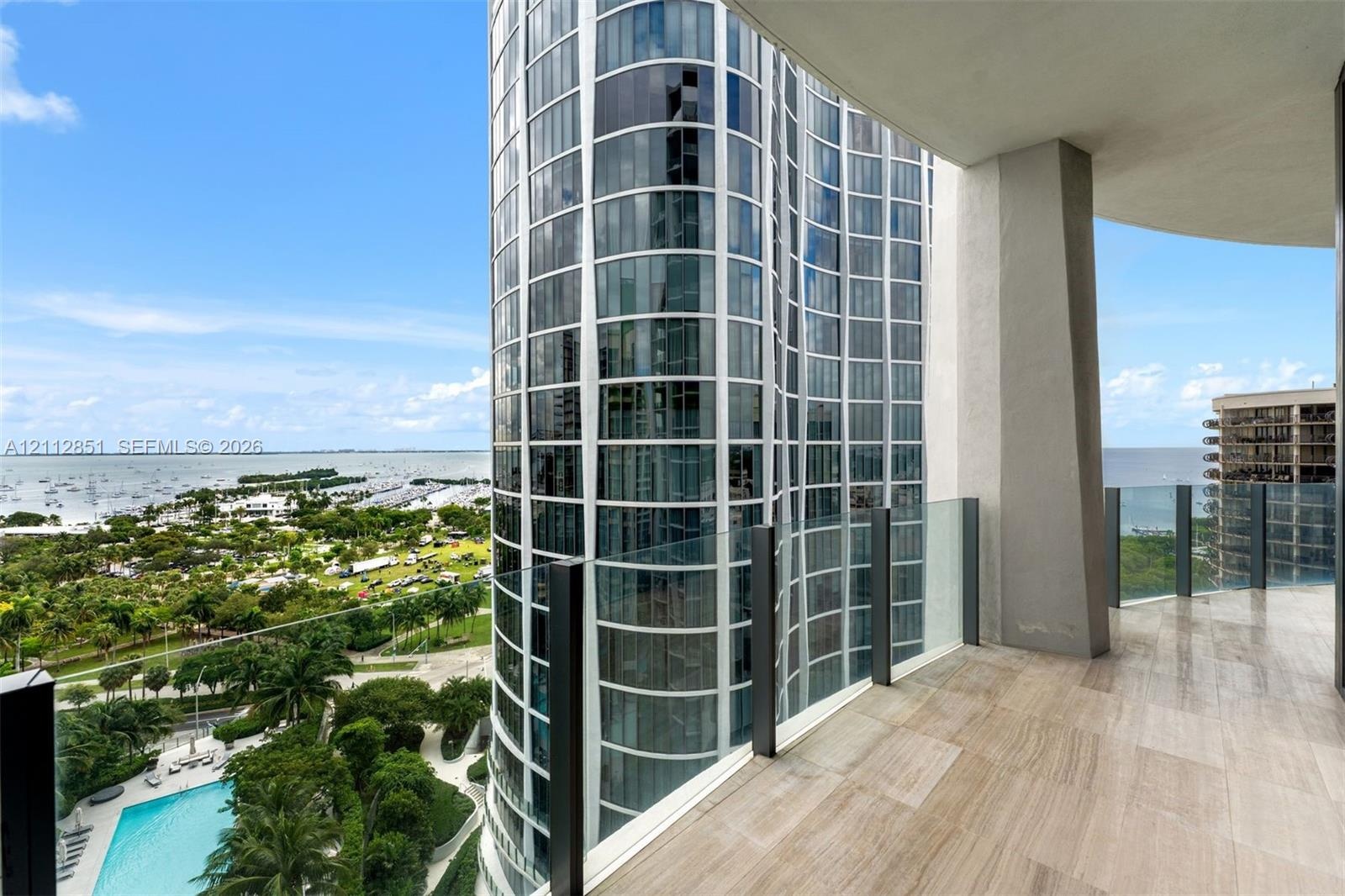 Covered balcony featuring stone flooring and a glass panel railing