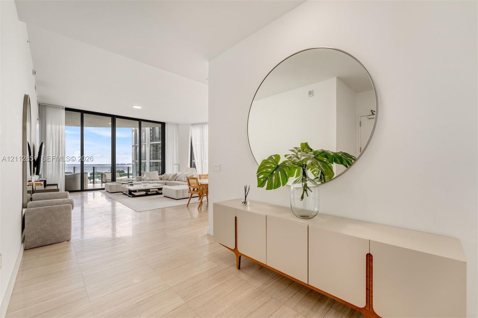 Open-concept interior featuring light-toned tile flooring, recessed ceiling lighting, and floor-to-ceiling glass panel walls